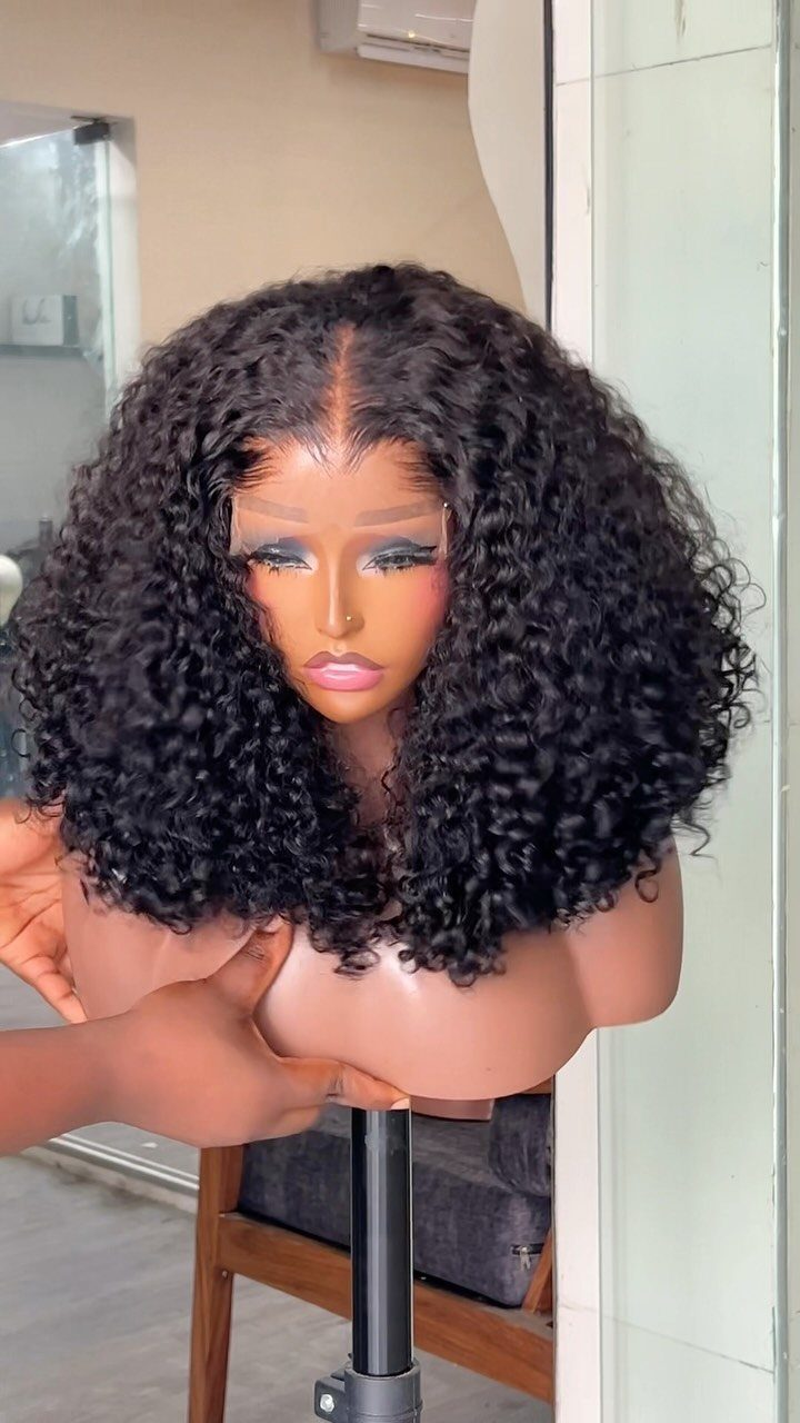 Mannequin bust wearing a voluminous black curly wig with a center part