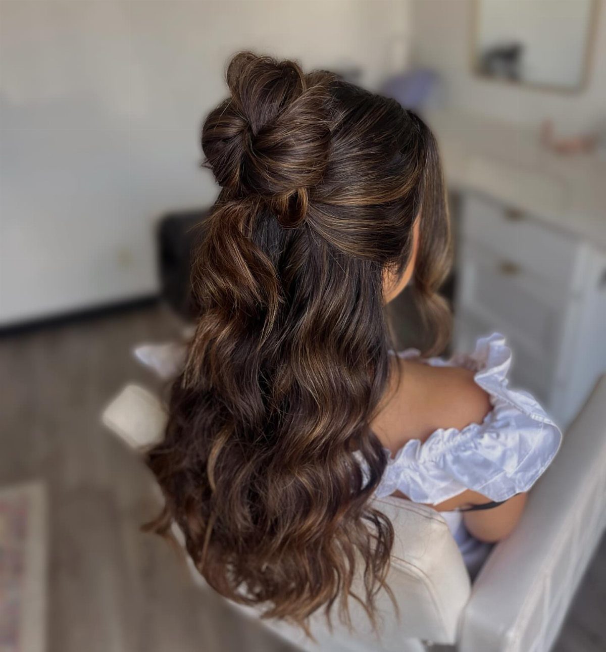 Half-up bun with long dark brown waves left flowing down the back