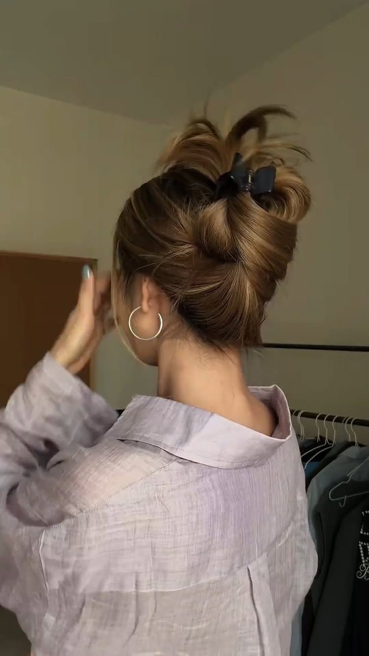 Loose brown hair gathered into a full bun with a dark clip