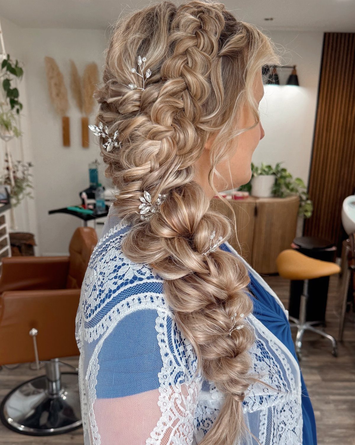 Blonde side braid with silver floral pins cascading over a blue top