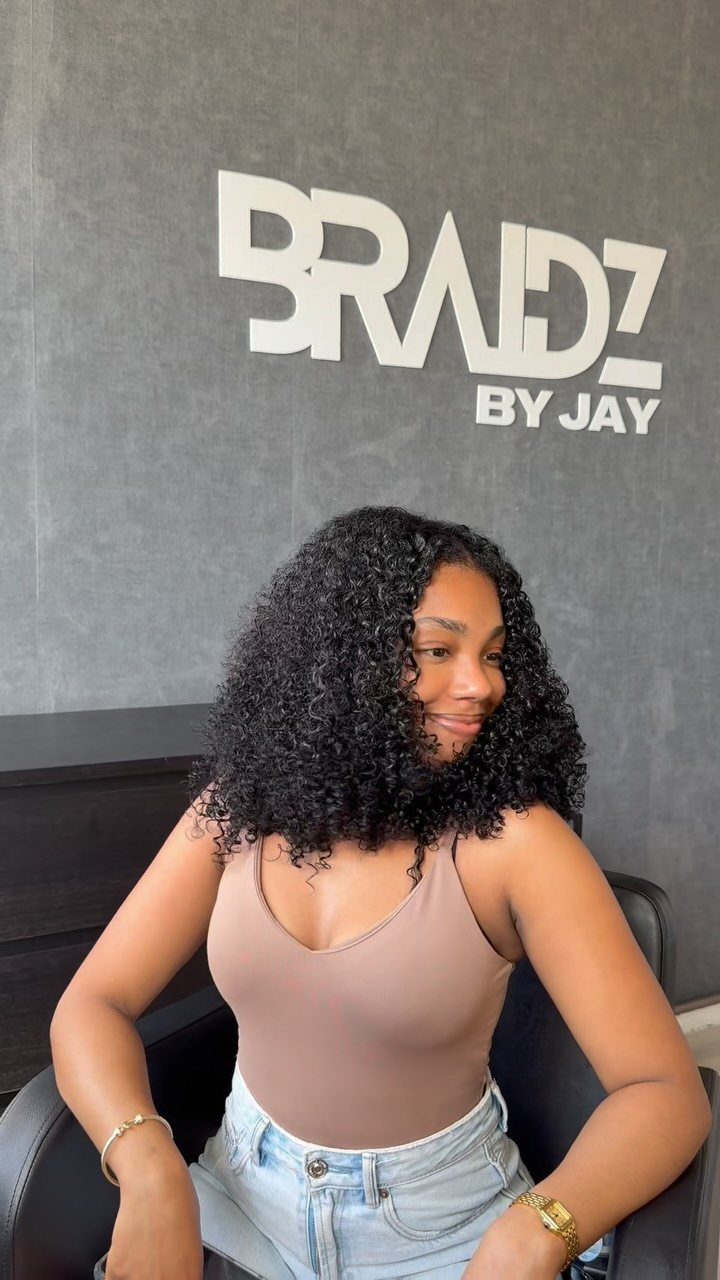 Woman wearing voluminous shoulder-length black curls in a salon chair