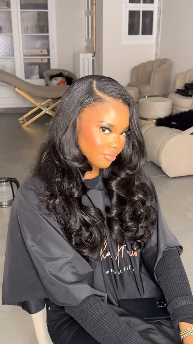 Long black layered hair falls in glossy curls over a woman’s shoulders