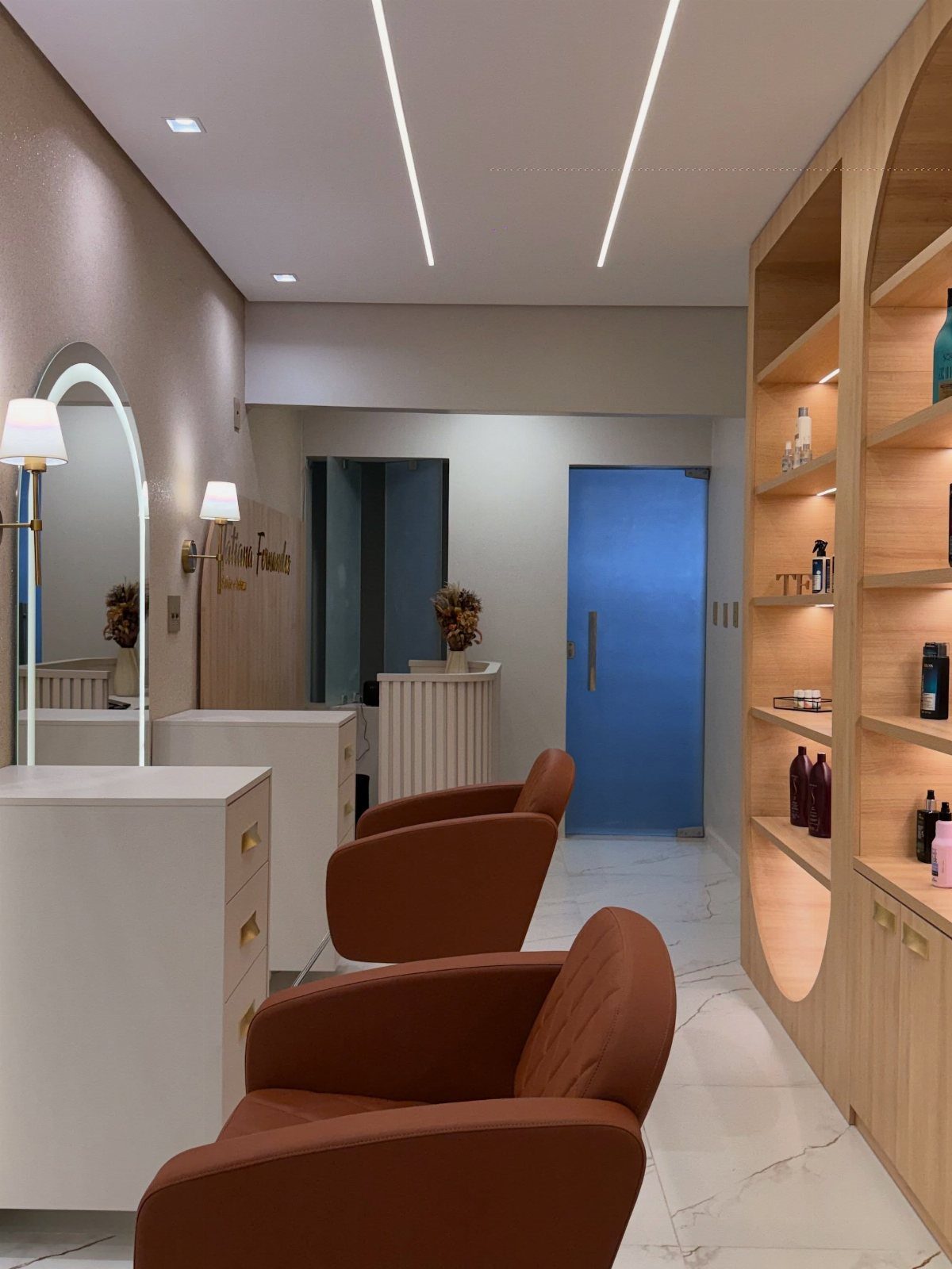 Salon interior with a rounded reception counter, arched mirror, and rust-brown styling chairs