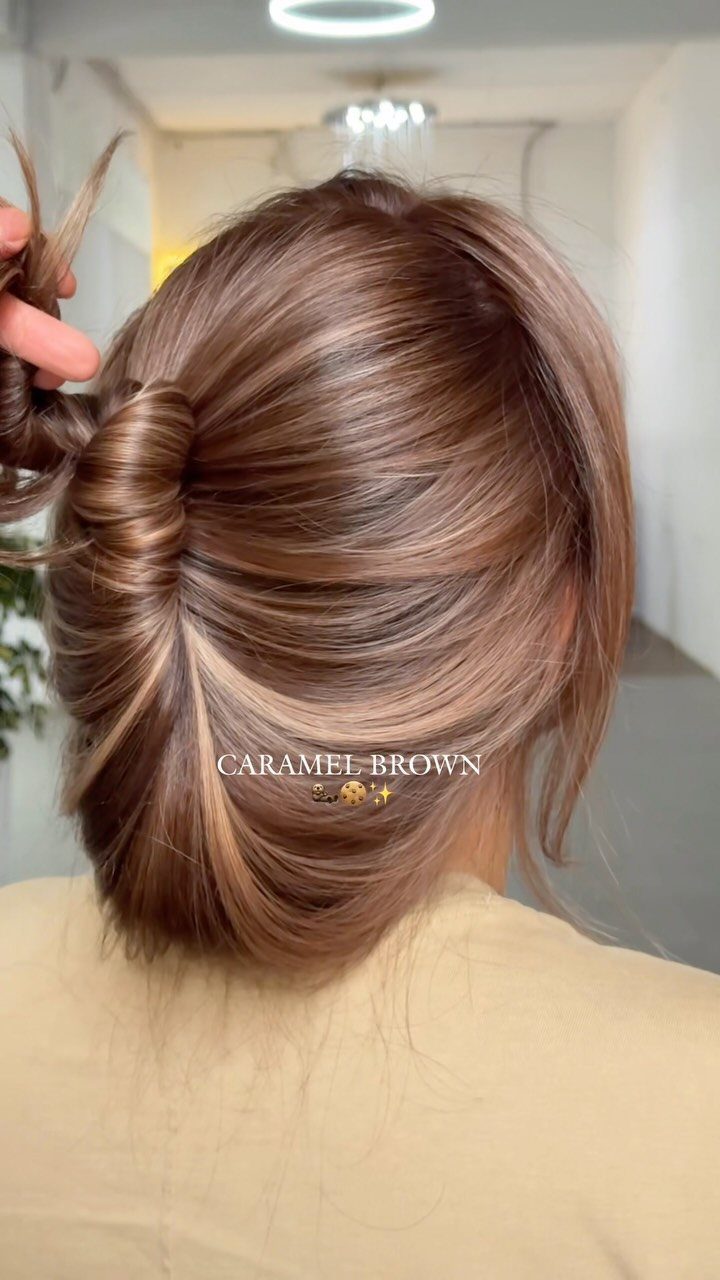 Glossy brunette updo with fine caramel highlights in a salon