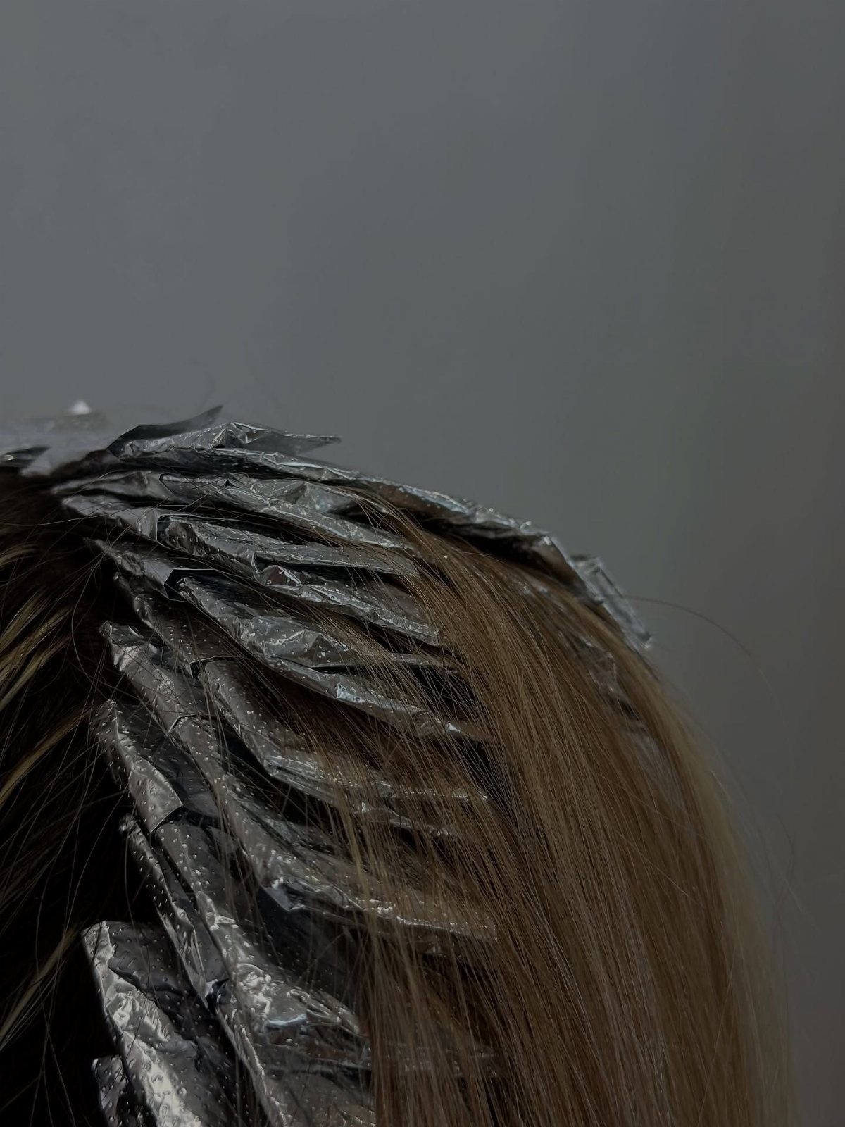 Brown hair sectioned with silver foils during a salon highlighting process