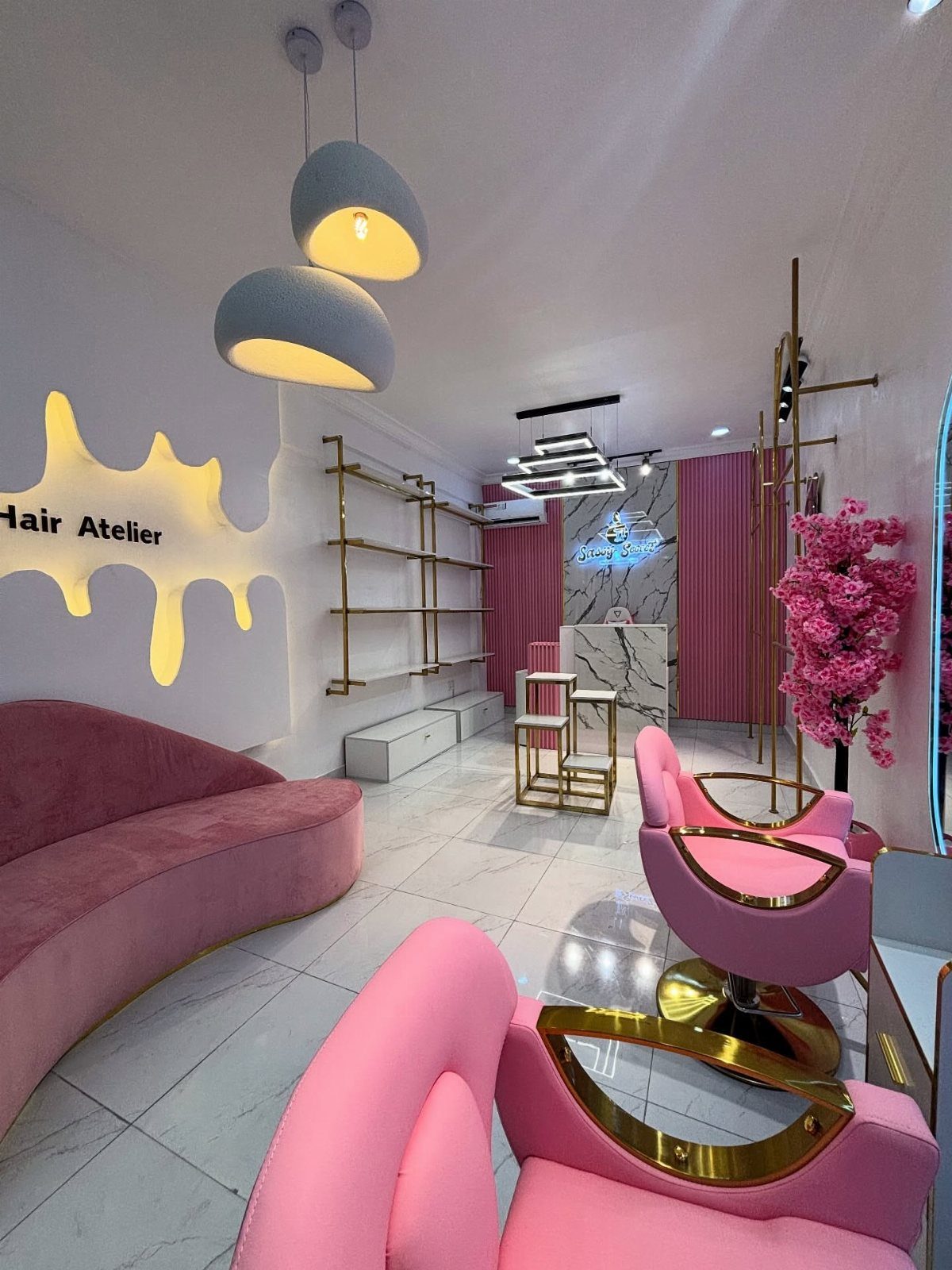 Pink velvet salon seating, gold tables, marble surfaces, and pendant lights