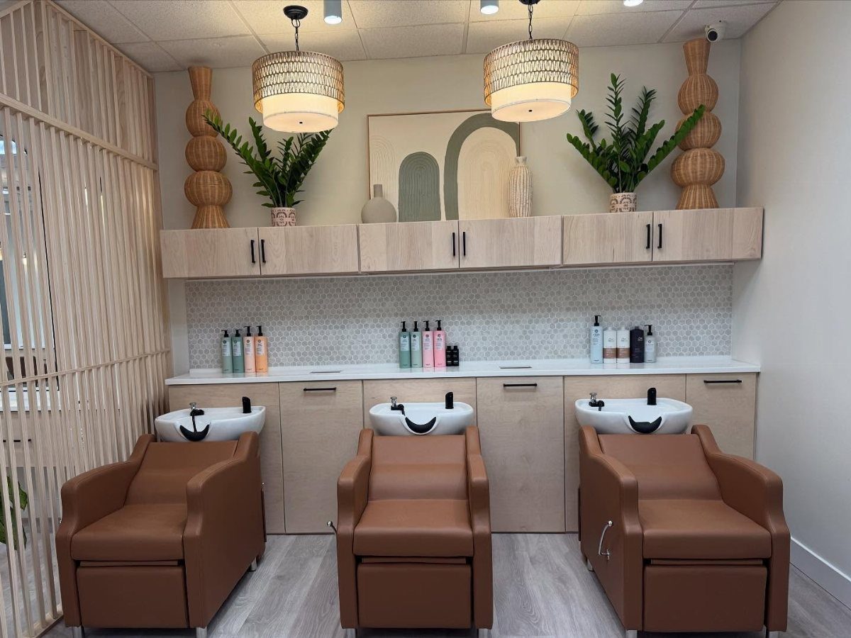 Aesthetic hair salon with shampoo stations, plants, pendant lights, and warm neutral decor