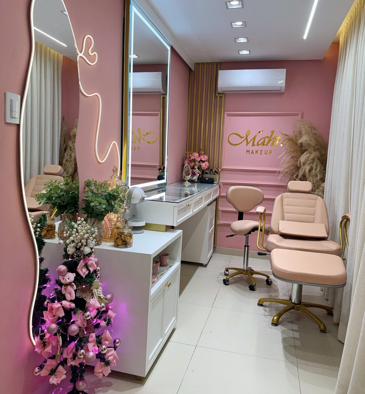 Pink salon interior with tall mirrors, beige chairs, and decorated pink tree