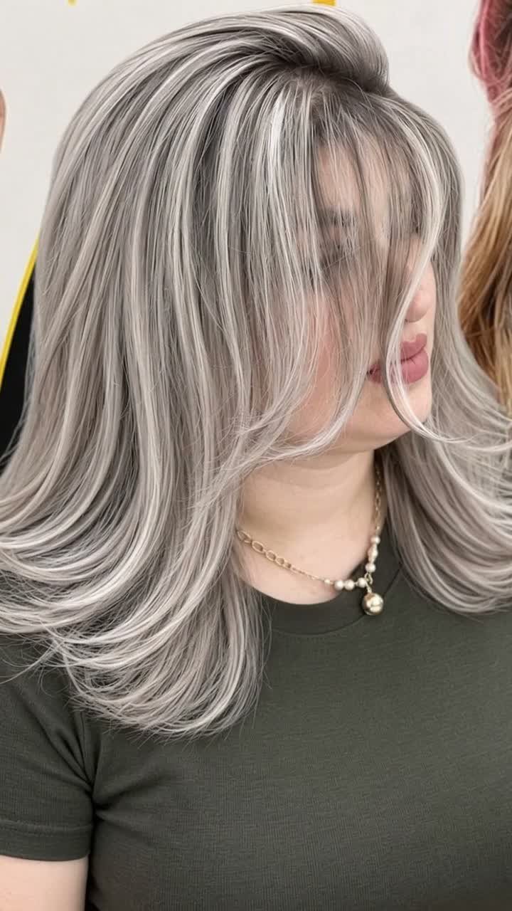 Layered silver-gray hairstyle with curtain bangs and soft waves on a person