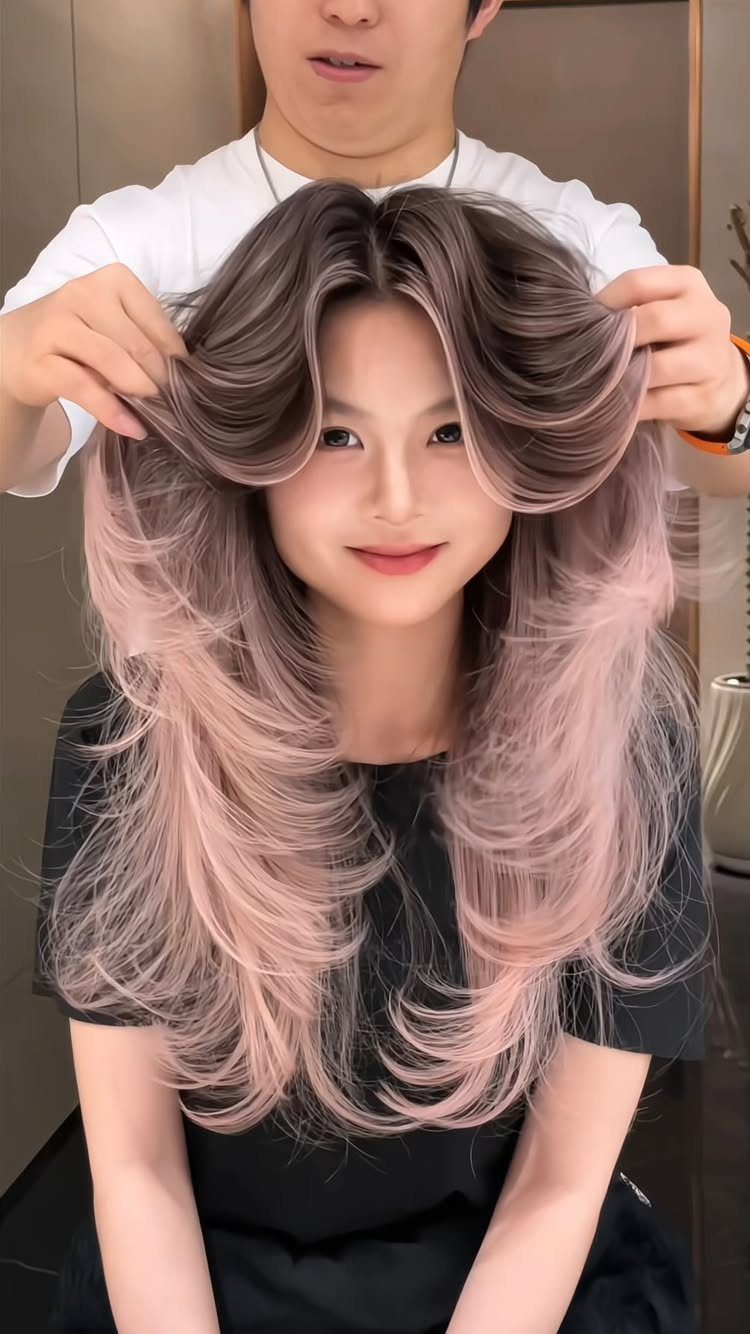 Woman with long layered silver-gray and pink hair styled by a salon stylist