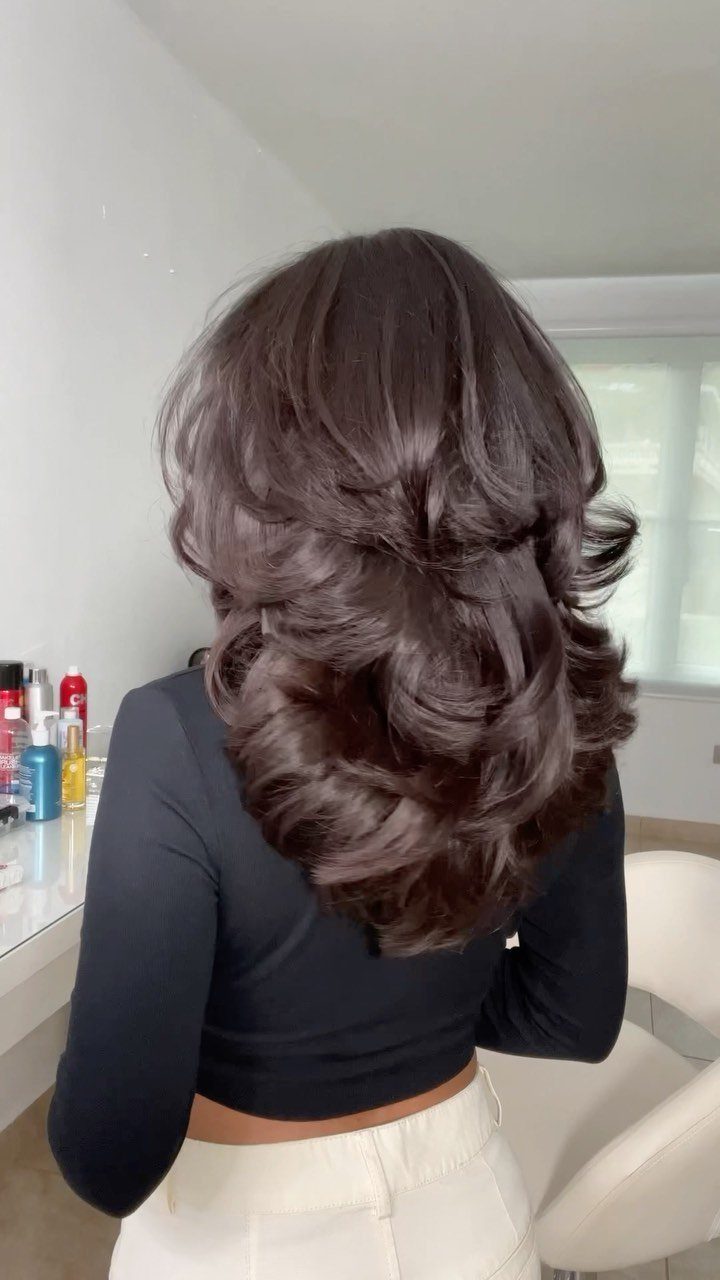 Long dark brown hair styled in voluminous curls at a bright salon