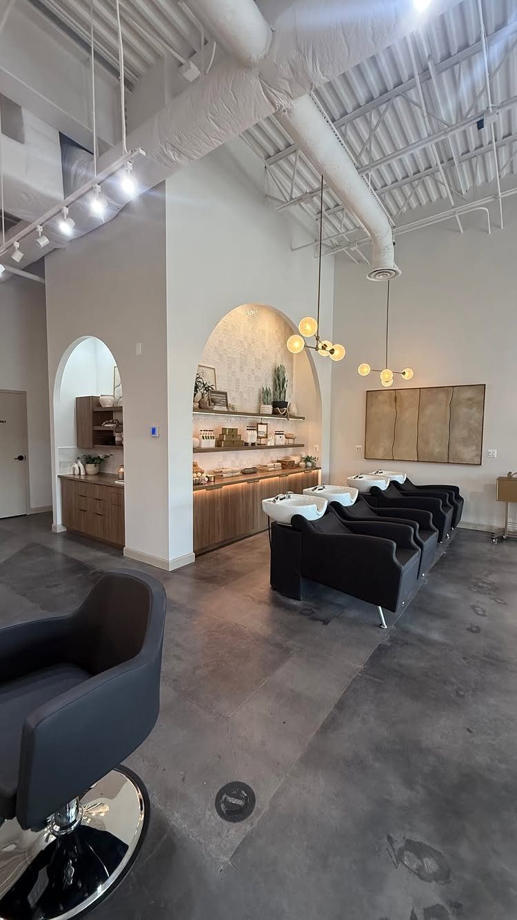 Modern hair salon with black styling chairs, arched mirrors and warm globe lights