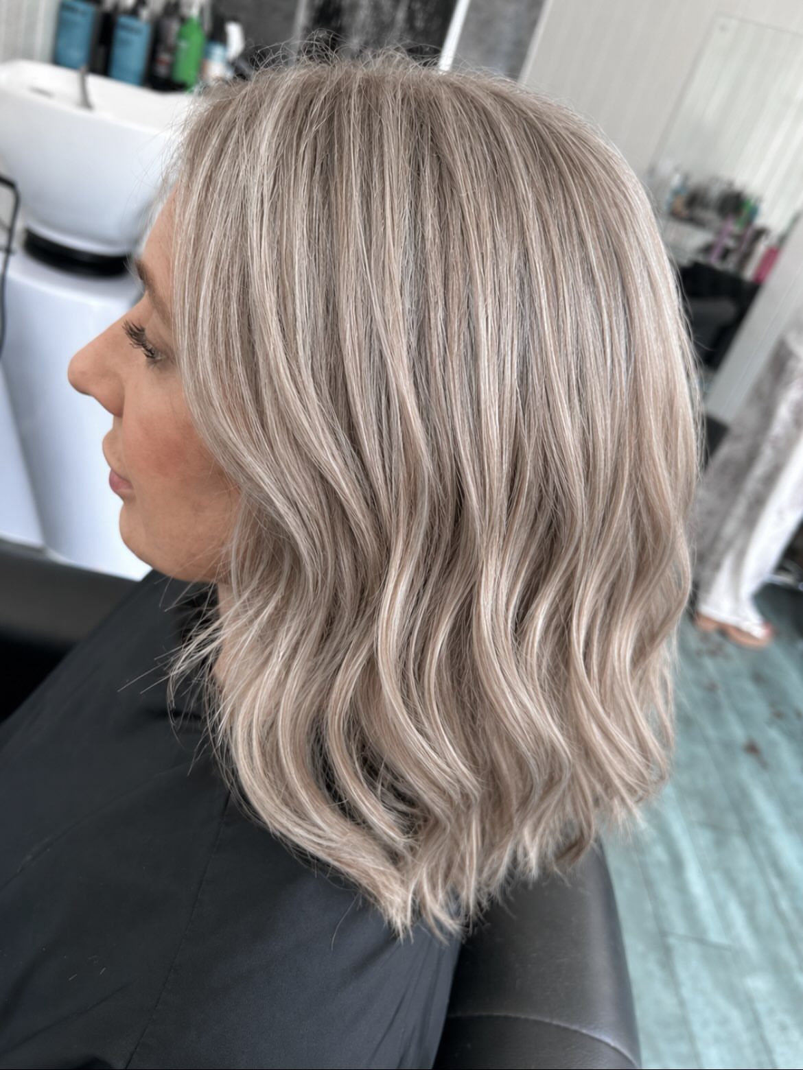 Woman with wavy ash blonde hair featuring cool gray and silver undertones.