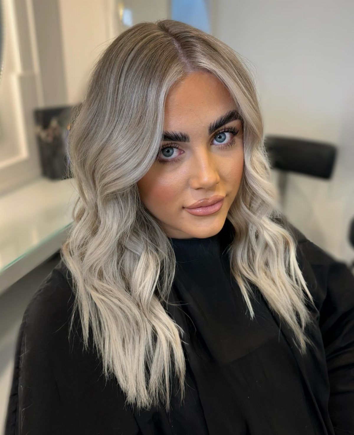 Woman with long wavy ash blonde hair with cool silvery highlights and tones.