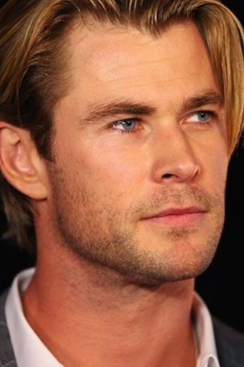 Man with swept-back blond hair and light stubble in a close-up portrait