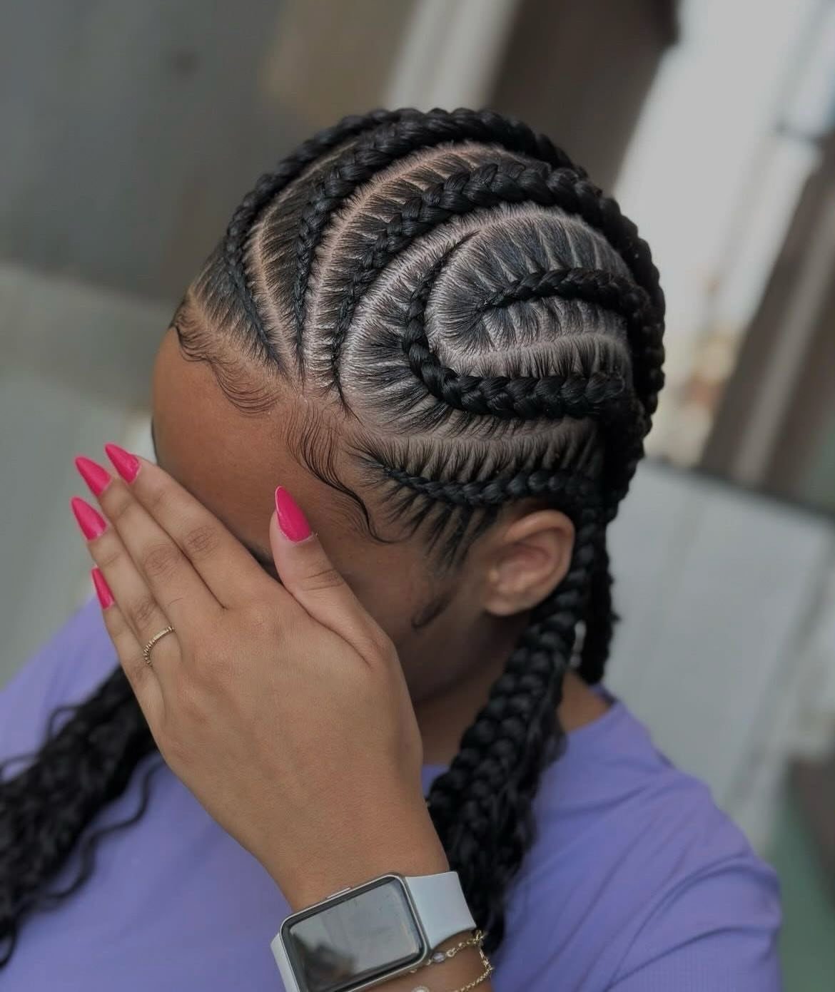 Curved scalp cornrows circle the crown, with long braids hanging down