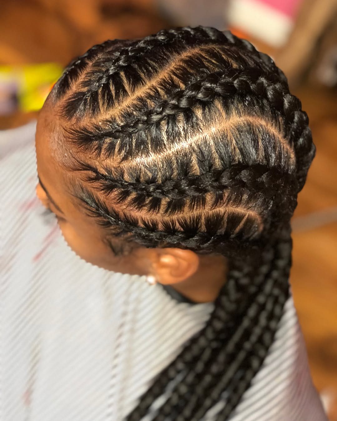 Cornrows run across the scalp and gather into long braids at the back