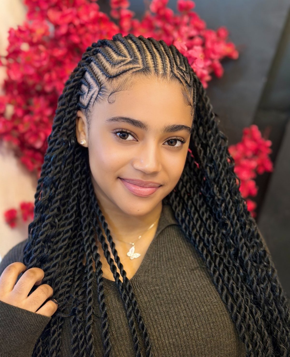 Young woman poses with patterned cornrows and long black twists