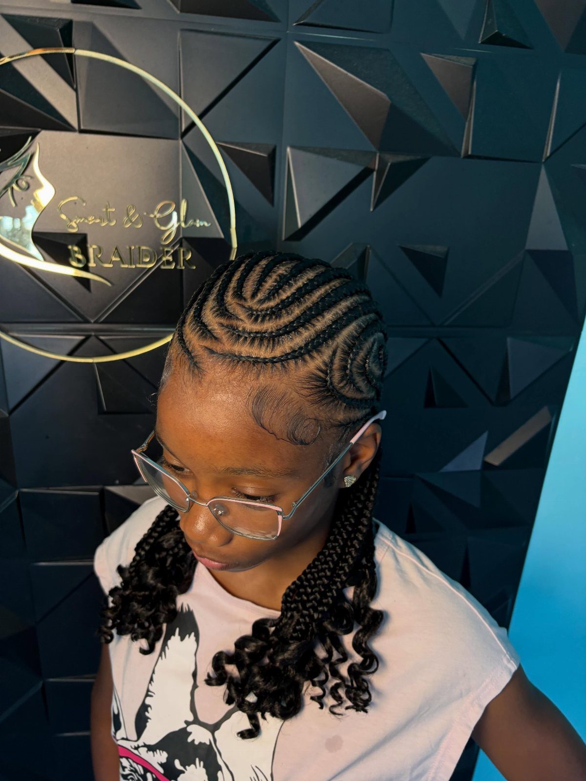 Curved cornrows sweep across the scalp into long braids with curled ends