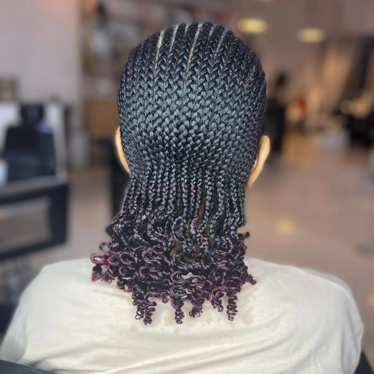 Patterned cornrows extend to mid-back and finish in curled purple-accented braids