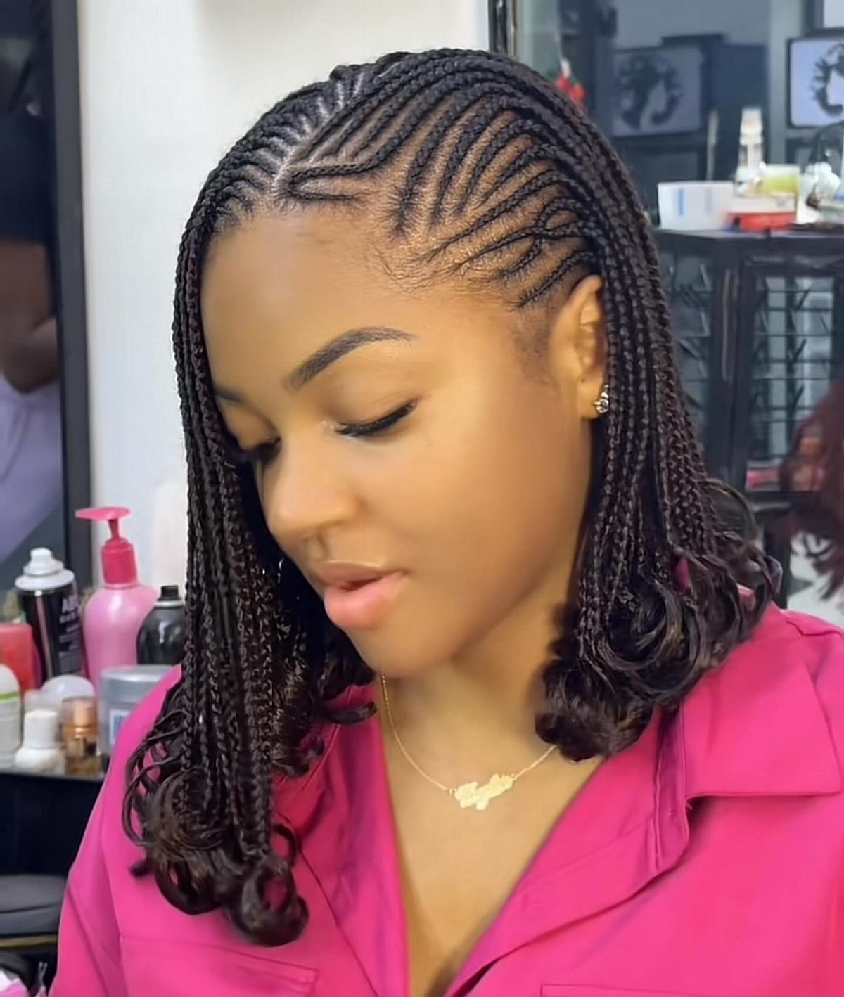 Side cornrows feed into long dark braids with curled ends on a woman
