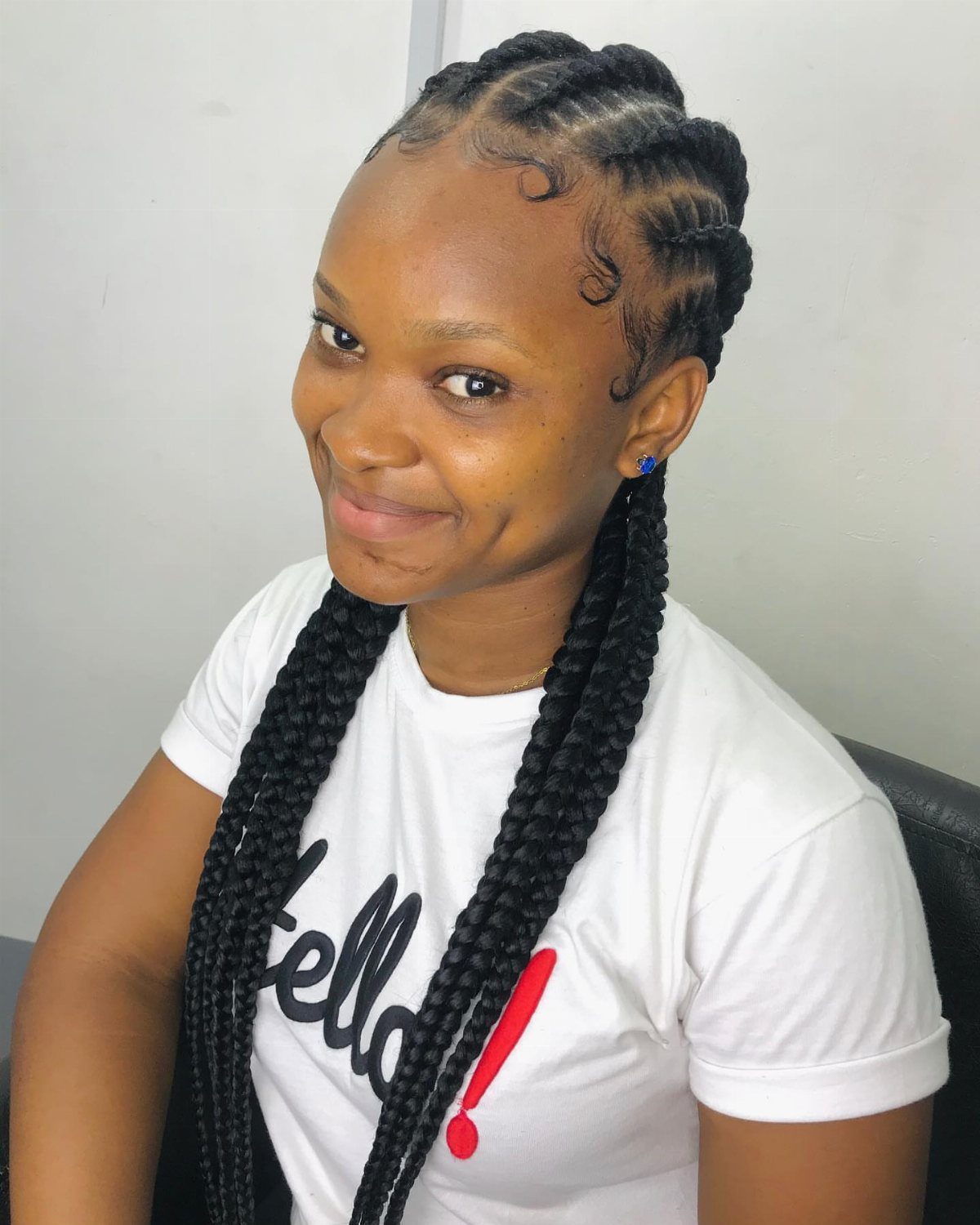 Woman with small cornrows and long black braids over her shoulders