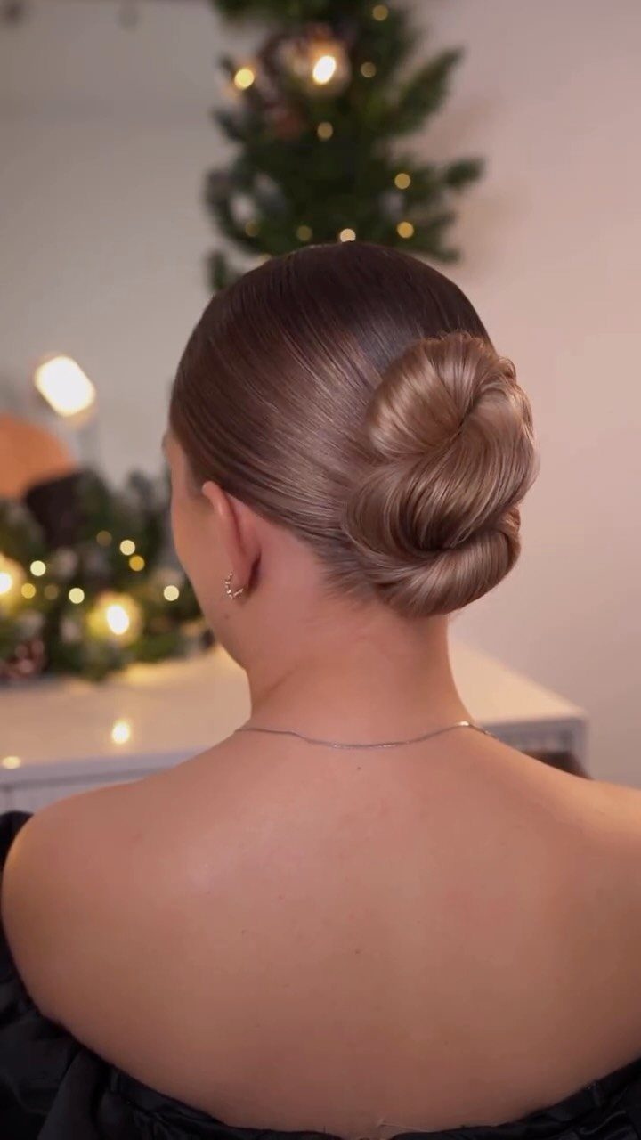Neatly coiled ballerina bun on smooth brown hair, shown from behind