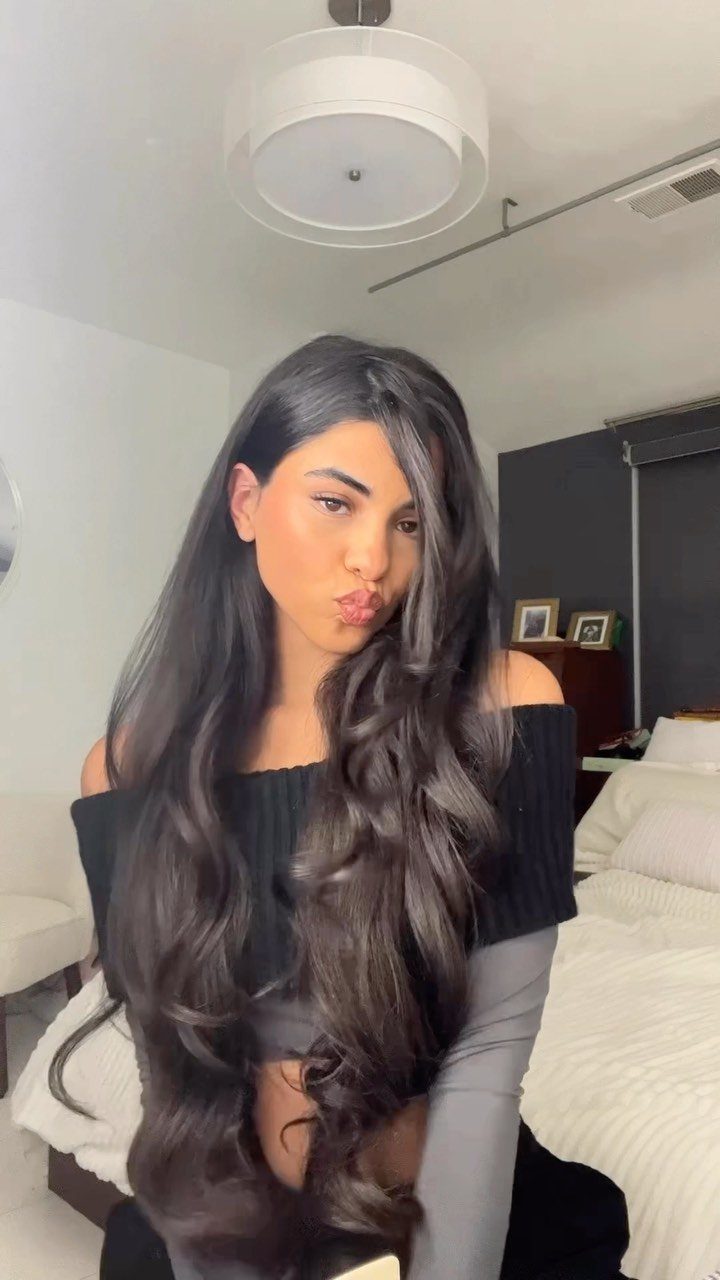 Woman posing with long, voluminous waves parted deeply to one side