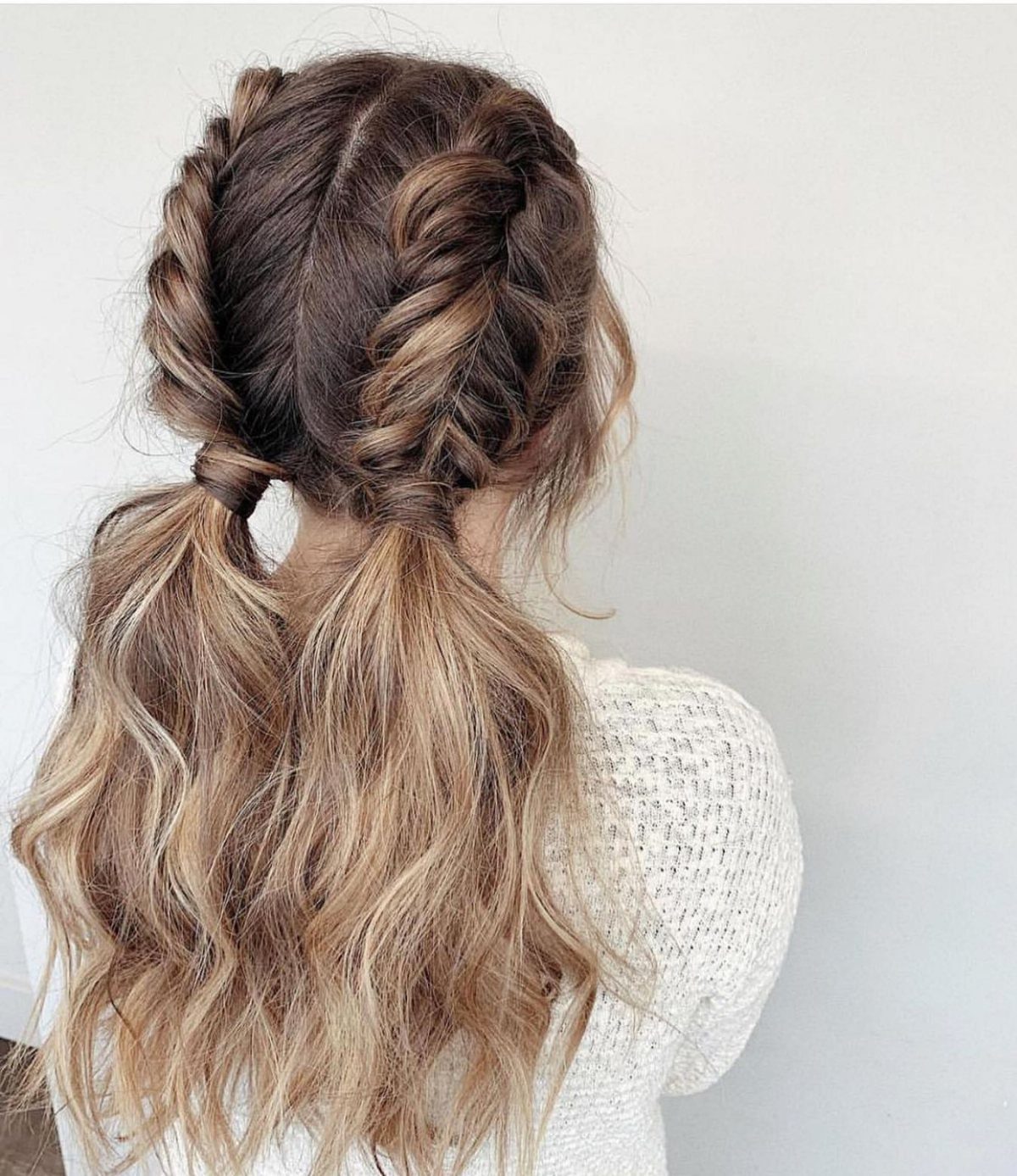 Two French braids ending in loose wavy pigtails on long ombré hair
