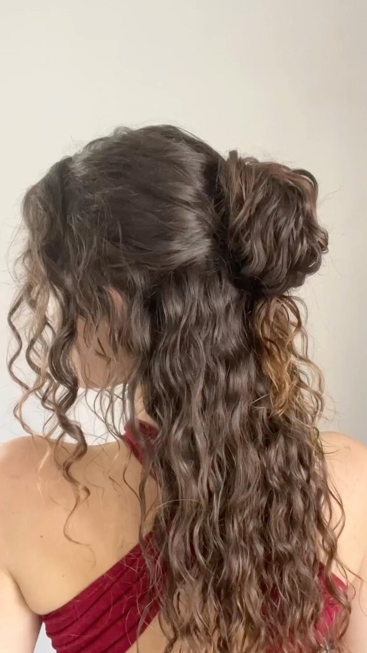 Half-up bun gathers the upper hair while long brown waves hang loose