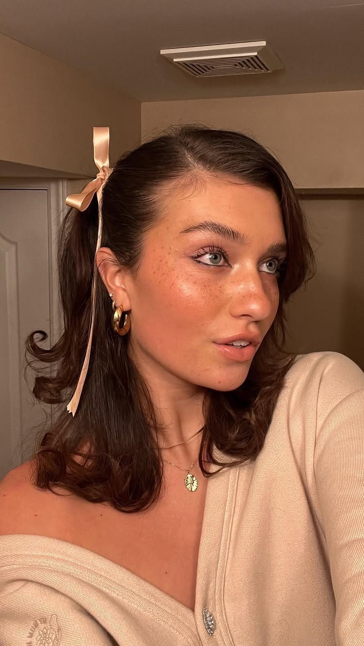 Woman with voluminous dark hair, curled ends, and a pale ribbon