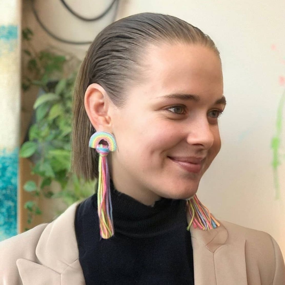 Woman showcasing sleek slicked-back hair with colorful dangling earrings