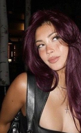 Woman with dark plum layered hair and face-framing pieces