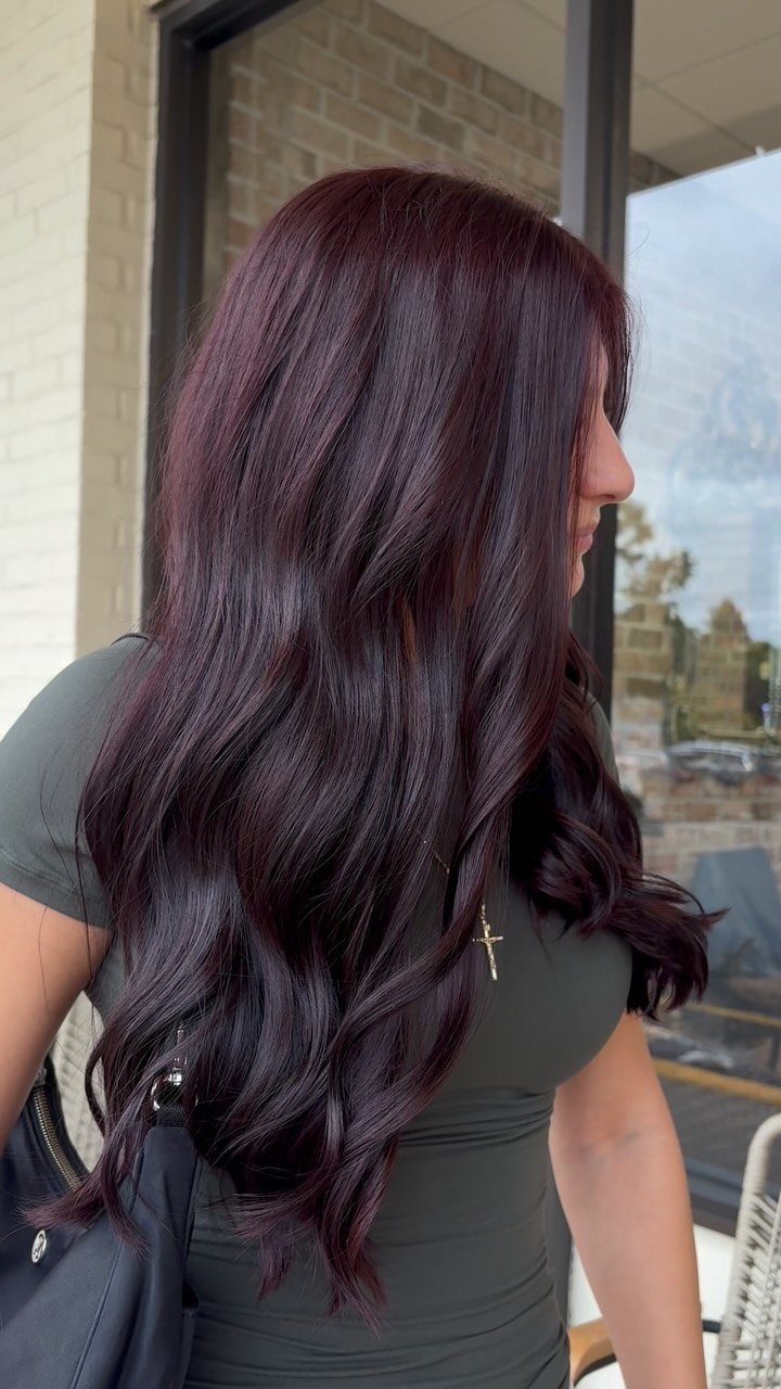 Long wavy plum-brown hair with subtle burgundy highlights viewed from the side