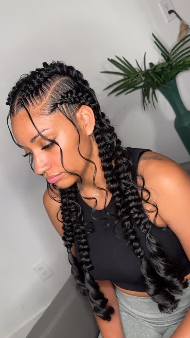 Long dark scalp braids transition into thick curled braids over a woman's shoulders.