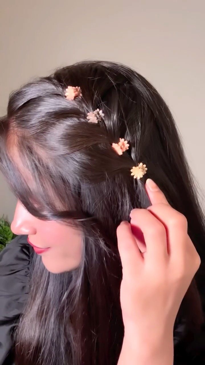 Woman wearing small flower hair clips along a section of long dark hair