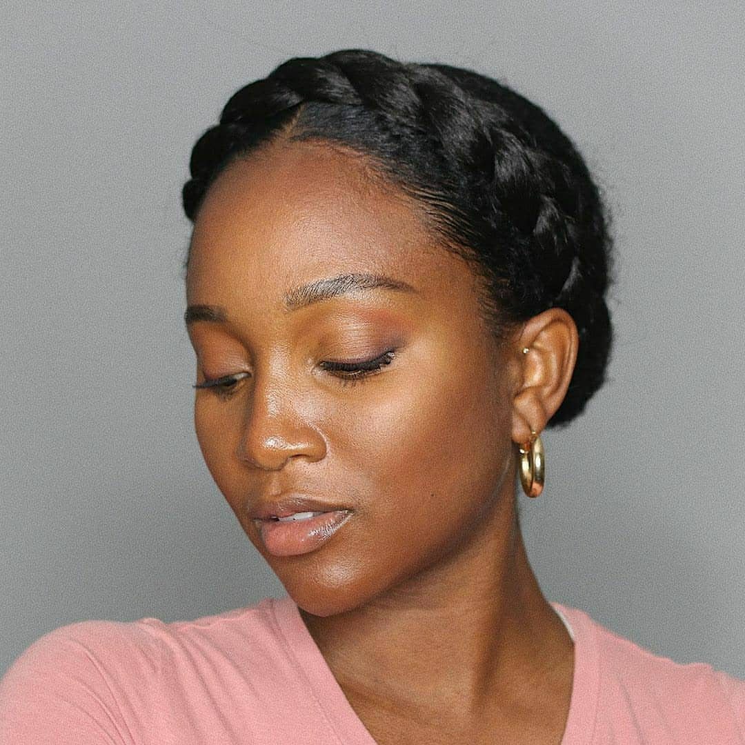 Crown braid wraps around a woman's head above her pink top