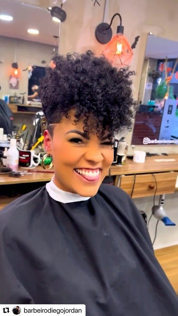 Woman smiling in a salon with voluminous, tightly curled black hair