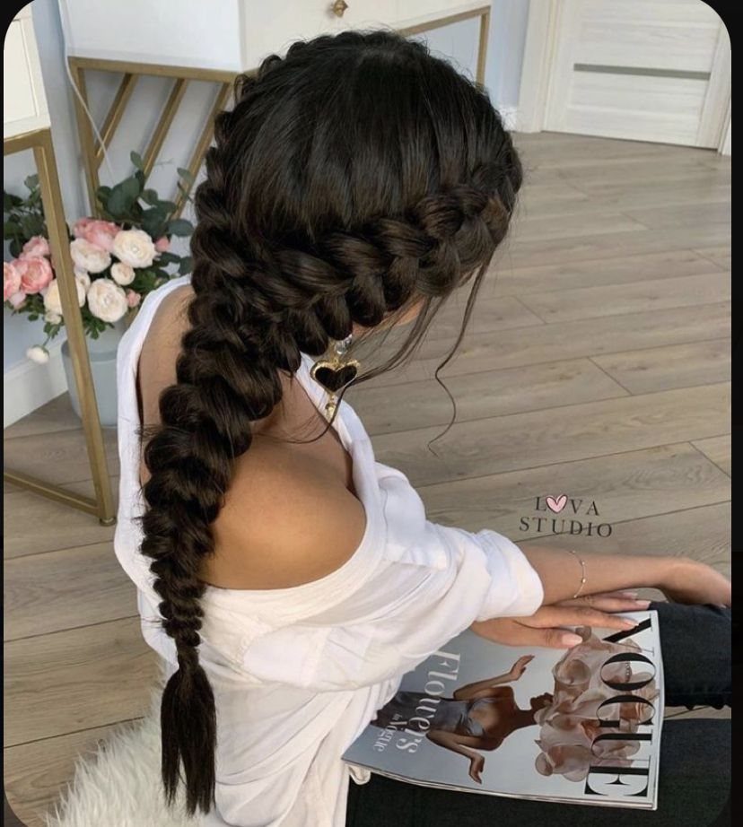 Thick dark Dutch braid runs down the back of a seated person
