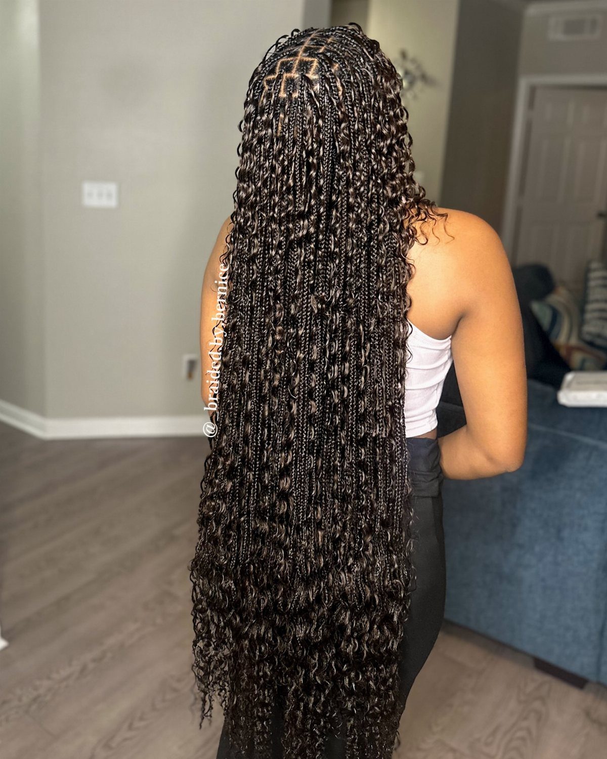 Long dark goddess braids with curly ends cascade down a person's back
