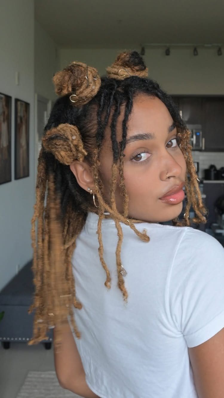 Person with dark locs gathered into loose buns and long hanging sections