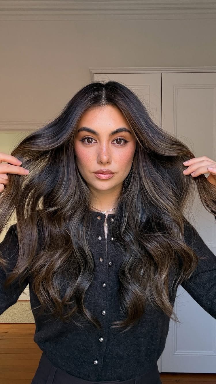 Woman displaying long, dark hair styled in loose, softly defined waves