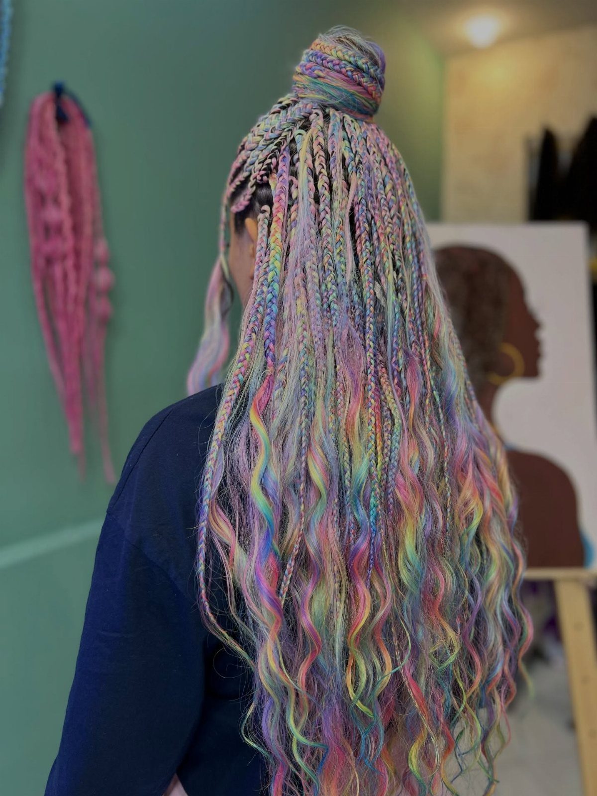 Long pastel mermaid braids cascade in waves down a person’s back