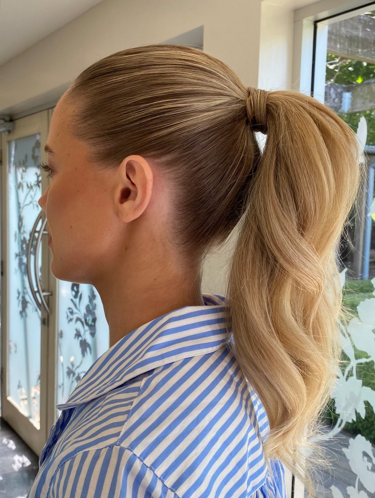 Woman with a sleek high blonde ponytail and softly waved lengths
