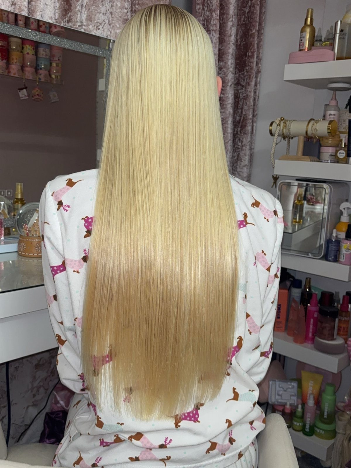 Long straight blonde hair falls down a seated person's back in a salon