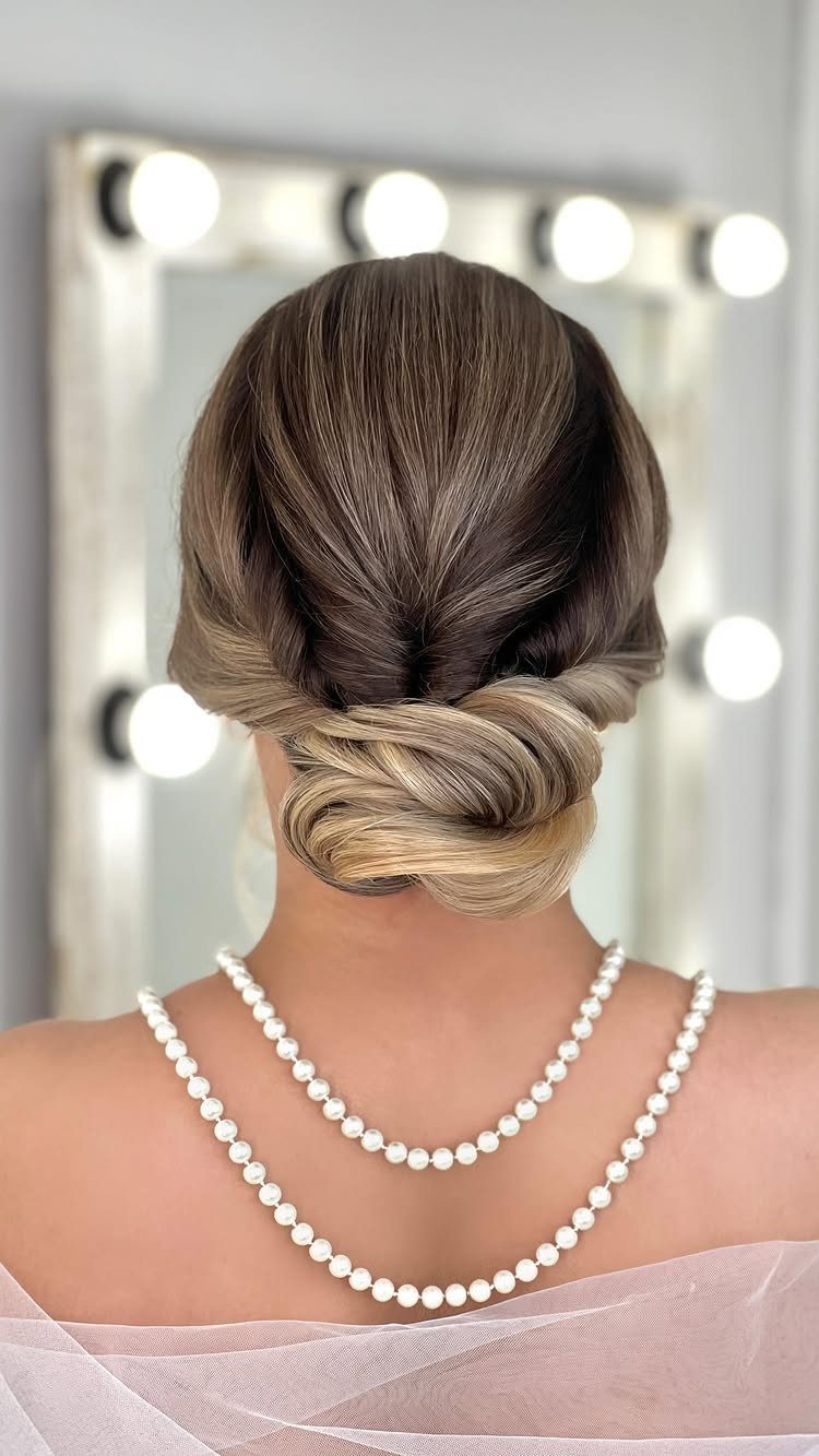 Brown hair twisted into a low updo bun above a pearl necklace