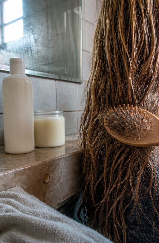 Stiff uneven hair section with wooden brush, caught hairs, shampoo bottle and jar