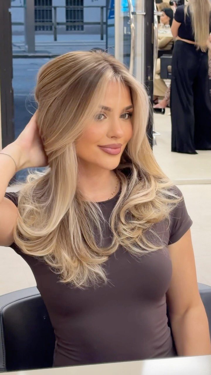 Woman showing long blonde hair with bright face-framing highlights in a salon