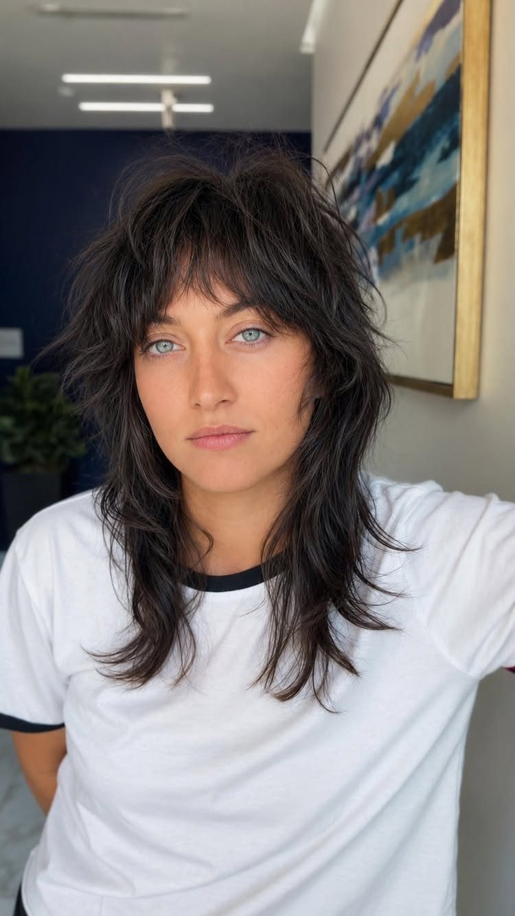 Person with a dark, textured shag haircut and wispy bangs