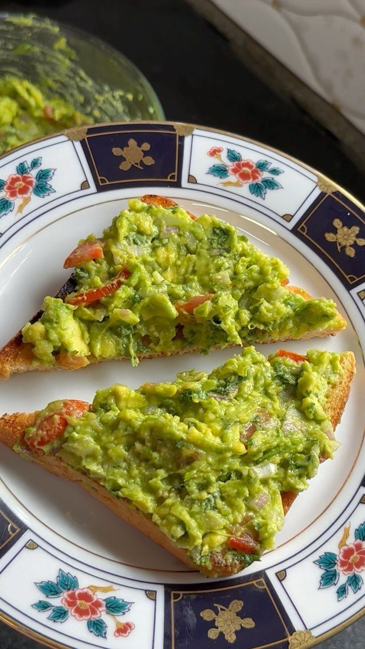 Avocado-topped toast on a floral plate with a bowl of extra spread
